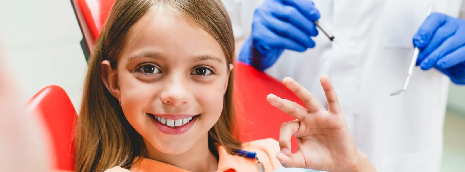 Niña sonriendo en el sillón dental junto a dentista